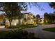 Beautifully landscaped front yard view of a home with a circular driveway and manicured garden beds lit at twilight at 6126 Kirkstone Ln, Windermere, FL 34786