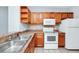 Bright kitchen featuring stainless steel sink, white appliances, and warm wood cabinets at 6157 Metrowest Blvd # 106, Orlando, FL 32835