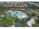 Aerial view of a resort-style pool with a splash pad, clubhouse, palm trees, and lounge chairs at 7509 Oak Spring Ln, Davenport, FL 33837
