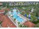 Aerial view of a resort-style pool with palm trees, cabanas, lounge chairs, and a tile roof clubhouse at 7509 Oak Spring Ln, Davenport, FL 33837