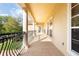 Long balcony with brick flooring, white pillars, iron railing, and views of the surrounding landscape at 8424 Lake Burden Cir, Windermere, FL 34786