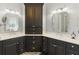 Bathroom with dual vanity, dark wood cabinetry, granite countertops, and decorative mirrors at 8424 Lake Burden Cir, Windermere, FL 34786