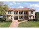 Elegant two-story home with a red tile roof, balcony, brick driveway, and well-maintained landscaping at 8424 Lake Burden Cir, Windermere, FL 34786