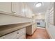 Well-lit laundry room with ample cabinet space, granite counters, laundry sink, and modern washer and dryer at 900 S Lake Adair Blvd, Orlando, FL 32804