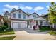 Charming two-story home featuring a three-car garage and a welcoming front porch with an American flag at 9192 Bradleigh Dr, Winter Garden, FL 34787