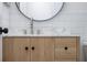 A bright bathroom with a light wood vanity, marble countertop, round mirror, and modern matte-black hardware at 12401 Harney Dr, Orlando, FL 32828