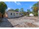 Home's back exterior featuring a gravel backyard, small patio, pergola, utility shed and white-painted trim at 1300 Conrad Dr, New Smyrna Beach, FL 32168