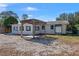 Back exterior view showcasing a partially fenced gravel yard, pergola, and access to the back of the home at 1300 Conrad Dr, New Smyrna Beach, FL 32168