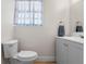 Bright bathroom features a toilet and vanity with gray cabinets and a window with striped curtains at 1300 Conrad Dr, New Smyrna Beach, FL 32168