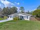 Charming home with well-manicured lawn, freshly painted white exterior, blue shutters and a sunny front porch at 1300 Conrad Dr, New Smyrna Beach, FL 32168