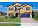Two-story home with a tan exterior, stone entryway, well-kept lawn, and a two car garage at 1515 Angler Ave, Kissimmee, FL 34746