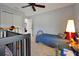 Bright bedroom with ceiling fan featuring a twin bed, glass desk, and a crib at 1832 Farnham Dr, Ocoee, FL 34761