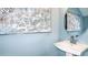 Stylish powder room with a pedestal sink, round mirror and decorative botanical wall art at 2504 Penguin Blvd, Davenport, FL 33837