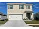 Two-story home showcasing a two-car garage, green shutters, and neutral paint at 2993 Moulin Rd, Davenport, FL 33837