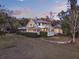 Charming two-story home featuring a screened porch, lush landscaping and a metal roof at dusk at 340 W 9Th Ave, Mount Dora, FL 32757