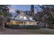 A beautiful two-story home with mature trees in front of the lawn and a long screened porch at 340 W 9Th Ave, Mount Dora, FL 32757