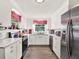Bright kitchen with white cabinetry, stainless steel appliances, and charming red and white checkered window valances at 340 W 9Th Ave, Mount Dora, FL 32757