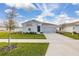 Single-Gathering home with a well-kept lawn, young tree, and a long driveway leading to a two-car garage at 350 Rustic Rail Dr, Lake Wales, FL 33859