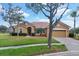 Charming single-story home with a red tile roof, manicured lawn, and mature landscaping under a blue sky at 4036 Bougainvillea Pl, Kissimmee, FL 34746