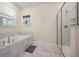 Bathroom featuring a large bathtub and glass-enclosed shower with tiled walls and floors at 4532 Target Blvd, Kissimmee, FL 34746