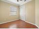 Neutral bedroom features laminate wood floors, a white closet door and a window at 4770 Cains Wren Trl, Sanford, FL 32771