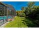Lush green lawn with an enclosed screen pool area with tropical foliage surrounding it at 5016 Fawn Ridge Rd, Orlando, FL 32819