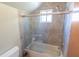 Well-lit bathroom featuring a tub with a shower and sliding glass door, complemented by neutral tiling at 5016 Fawn Ridge Rd, Orlando, FL 32819
