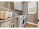 Well-organized laundry room featuring gray cabinetry, sleek countertops, and modern, front-load washer and dryer at 896 Tilden Oaks Trl, Winter Garden, FL 34787