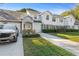 An exterior elevation of the townhouse featuring a well-manicured lawn, driveway, and attached garages at 923 Lexington Pkwy # 14, Apopka, FL 32712