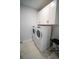 Well-lit laundry room with white cabinets, a modern washer and dryer set, and tile floors at 1114 Turquoise Waves Cv, Kissimmee, FL 34747