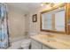 Bright bathroom with a tub/shower combo, vanity with marble countertops, and a framed mirror at 1415 Ocean Shore Blvd # 704, Ormond Beach, FL 32176