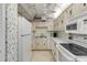 Efficient kitchen with white appliances, tile floor, and vintage decorative wall paper at 1415 Ocean Shore Blvd # 704, Ormond Beach, FL 32176