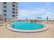 A kidney-shaped pool with blue umbrellas and lounge chairs for relaxing at 1415 Ocean Shore Blvd # 704, Ormond Beach, FL 32176