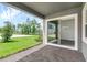 A shaded outdoor patio with brick flooring, a view of the lawn, and an open sliding glass door at 15491 Lebeau Loop, Winter Garden, FL 34787