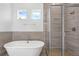 Bathroom featuring soaking tub, stone tile accent wall, and frameless shower at 15491 Lebeau Loop, Winter Garden, FL 34787