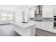 Modern kitchen with white cabinets, stainless steel hood, stone backsplash, and an island with sink at 15491 Lebeau Loop, Winter Garden, FL 34787