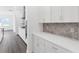 Modern kitchen with white cabinets, stainless steel appliances, stone backsplash, and hardwood floors at 15491 Lebeau Loop, Winter Garden, FL 34787