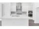 Modern kitchen with white cabinets, stainless steel hood, stone backsplash, and an island with sink at 15491 Lebeau Loop, Winter Garden, FL 34787