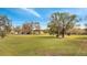 Scenic view of a large grassy lawn with mature trees under a bright, blue sky at 1775 Druliner Rd, St Cloud, FL 34771