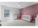 Bedroom with mauve accent wall, crib, dresser, and natural light at 2564 Bullion Loop, Sanford, FL 32771