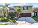 Two-story home featuring a well-manicured lawn, mature landscaping, and a two-car garage at 2564 Bullion Loop, Sanford, FL 32771