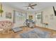 Sunlit bedroom featuring wood floors, ceiling fan, modern desk, and papasan chair at 3100 Nancy St, Orlando, FL 32806