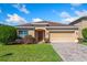 Charming single-story home with a well-manicured lawn, tan exterior and attached two car garage at 4605 Kalispell Rd, Kissimmee, FL 34758