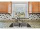 Close-up of the Kitchen Sink featuring granite countertops, tile backsplash, and natural light at 4900 Kempston Dr, Orlando, FL 32812