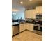 Functional kitchen with stainless steel appliances, tile floors, and ample cabinet space at 5356 Oakbourne Ave, Davenport, FL 33837