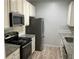 Well-lit galley kitchen with stainless steel appliances, granite countertops, and wood-look floors at 586 Brantley Terrace Way # 201, Altamonte Springs, FL 32714