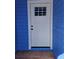 Close-up of a white front door framed by bright blue siding and a small landing area at 703 Pine Shores Cir, New Smyrna Beach, FL 32168