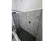 Close-up of the walk-in shower with pebble stone floor, gray tiling, and sleek black hardware at 703 Pine Shores Cir, New Smyrna Beach, FL 32168