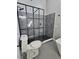 A modern shower space with gray tiling, black hardware and glass divider, with river rock flooring at 703 Pine Shores Cir, New Smyrna Beach, FL 32168
