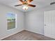 Bright bedroom featuring a window view, ceiling fan, and a door to a corridor at 7139 Se 122Nd Ln, Belleview, FL 34420